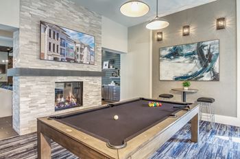 A pool table in a room with a fireplace and a painting on the wall at Crabtree Lakeside Apartments, North Carolina
